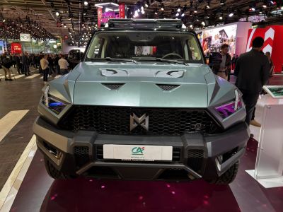 Front view of a rugged SUV with angular LED headlights, honeycomb grille, hood vents, and roof rack.