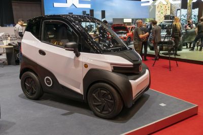 Compact electric urban vehicle with two-tone design and aerodynamic black wheels.
