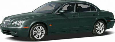 Dark green sedan with round headlamps and alloy wheels front side view