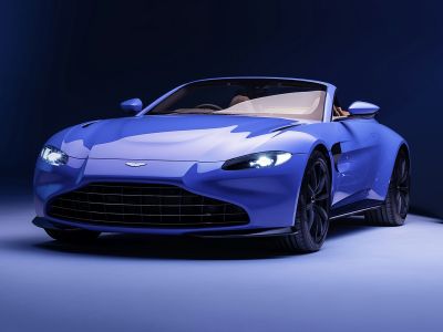 Streamlined front with illuminated headlights and wide grille on a sleek blue roadster.