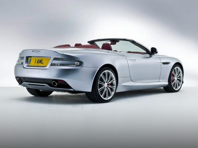 Silver convertible with dual exhaust and red interior, rear-side angle