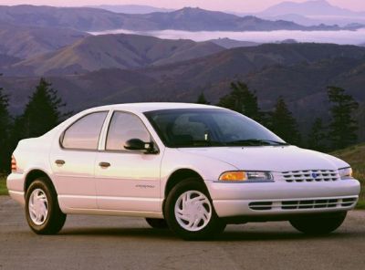 Front side view of a white sedan with mountain backdrop.