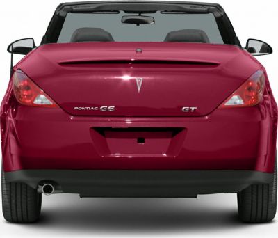 Rear view of a red convertible with visible taillights and open roof.