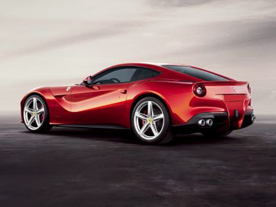 Rear and side profile of a luxury sports car with quad exhaust and alloy wheels.