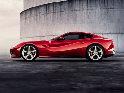 Side profile of red coupe with aerodynamic design and alloy wheels