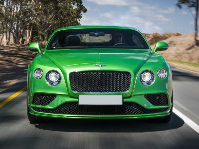 Bright green luxury sports sedan front with round headlights and mesh grille