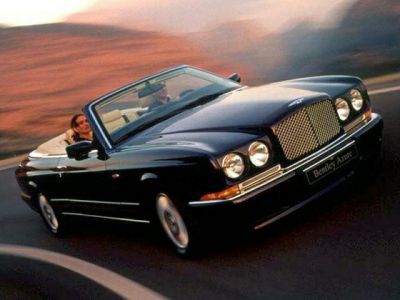 Classic front grille and round headlights on a luxury convertible in motion