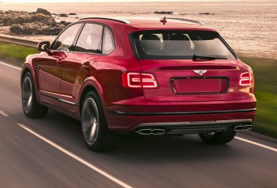 Luxury SUV rear with LED tail lights and dual exhaust on coastal road