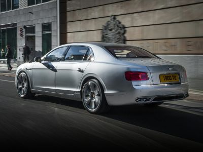 Silver luxury sedan rear side view with alloy wheels and quad exhausts.