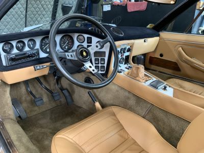 Vintage dashboard, classic steering wheel, manual gear shifter, tan leather upholstery.