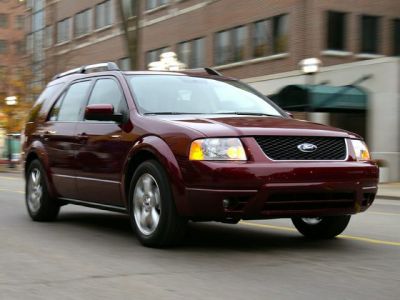 Front-side view of SUV driving on a city street with headlights on