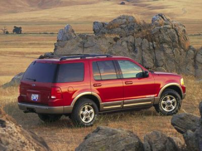 Red SUV rear side view in a rugged outdoor landscape.