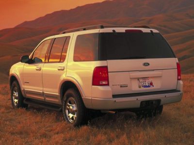 Rear view of an SUV with tinted windows and rugged tires in a natural landscape.