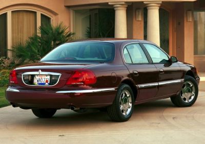 Rear angle of a red sedan with chrome trim and distinctive tail lights